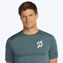 Headshot of Peloton instructor Denis Morton. He's smiling and wearing a teal Peloton athletic shirt.