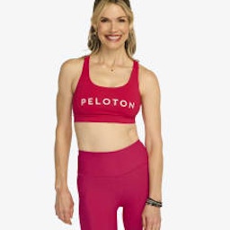 Headshot of Peloton instructor Kristin McGee. She's wearing a red two-piece Peloton workout outfit and smiling.
